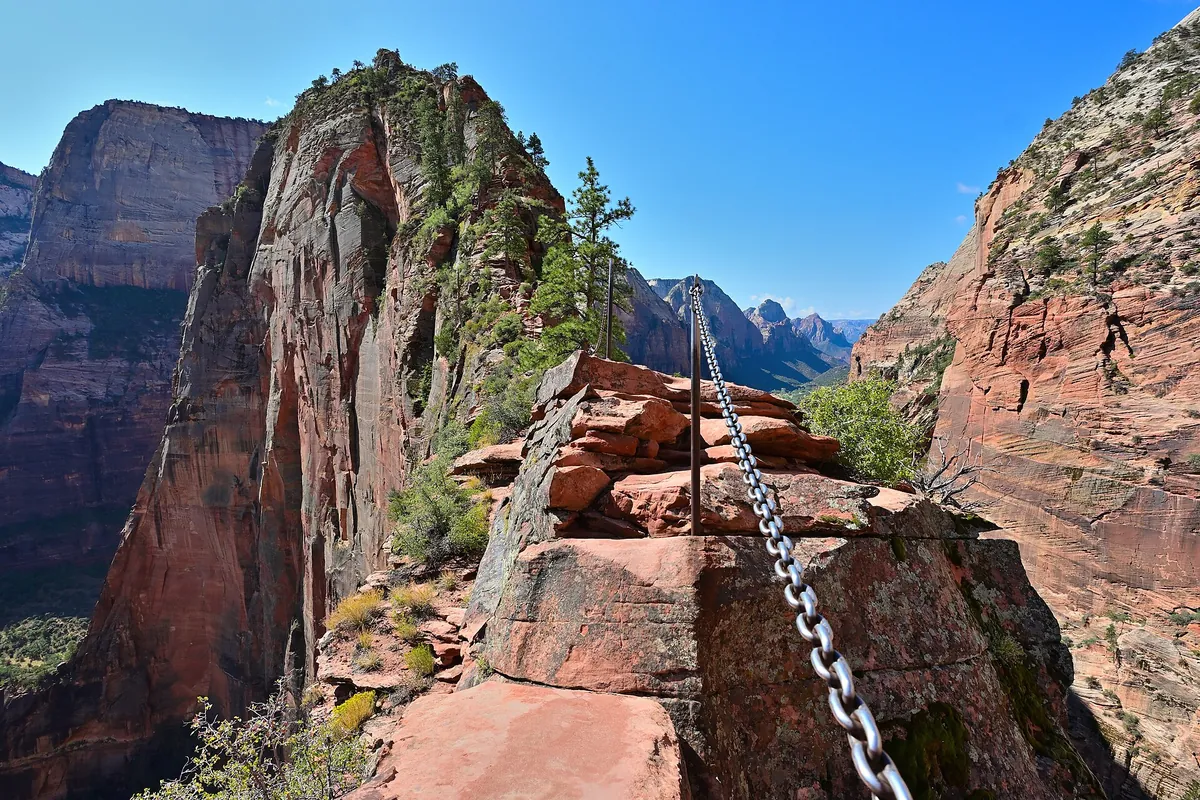 Metal chain bolted along the narrow ridge of the Angels Landing trail, with canyon walls beyond