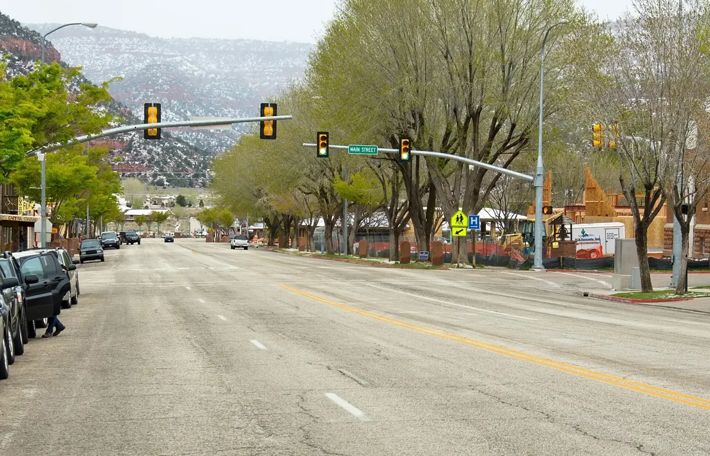 Kanab Main Street on US-89 lined with trees, with red-rock hills and a dusting of snow behind the town