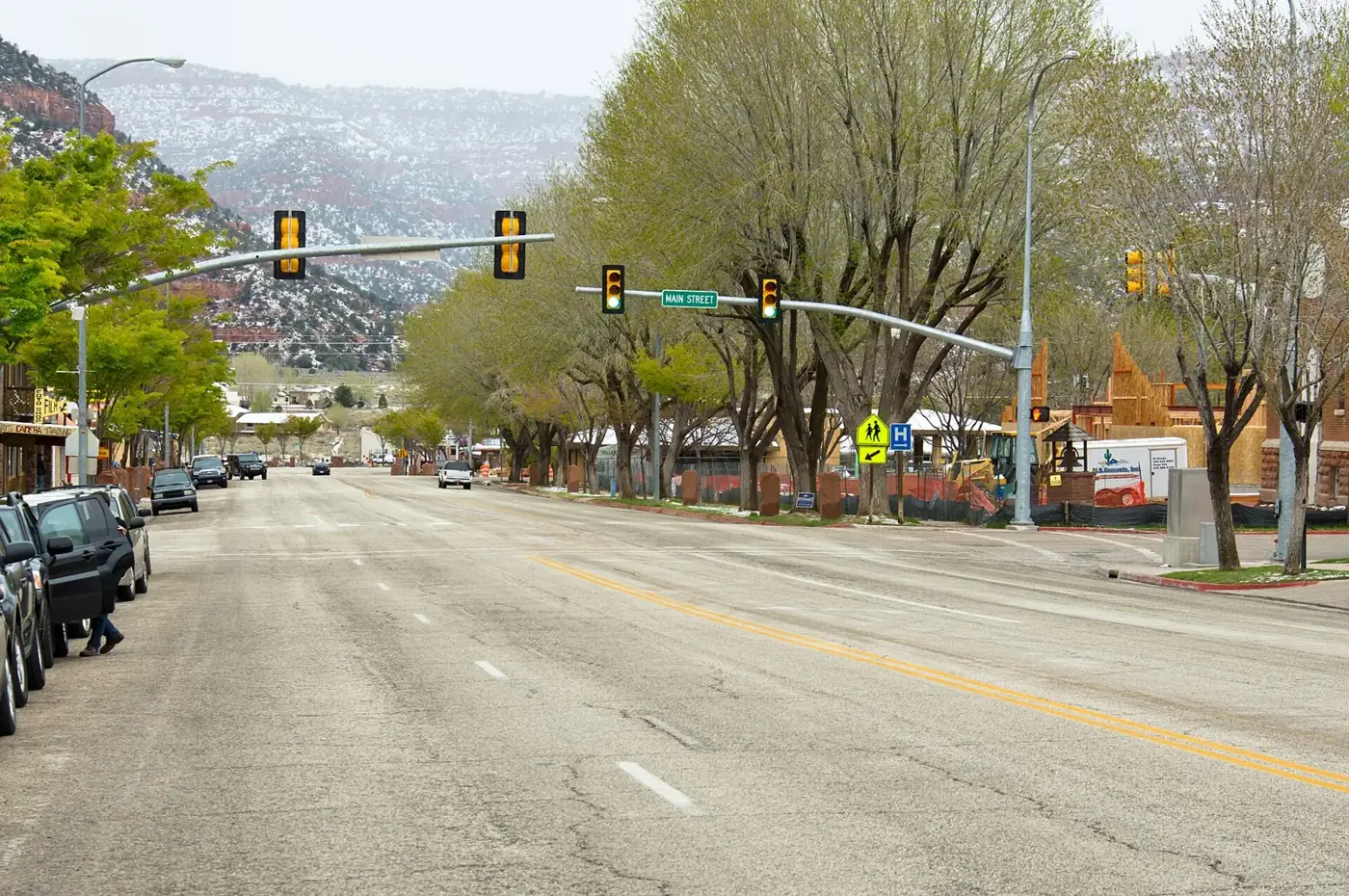 Kanab Main Street on US-89 lined with trees, with red-rock hills and a dusting of snow behind the town