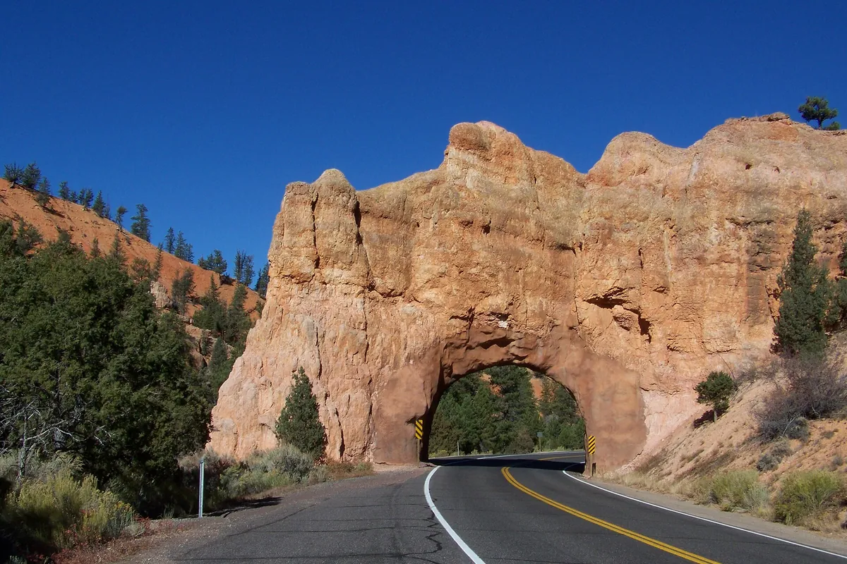 Highway 12 passing through a natural red rock arch tunnel in Red Canyon, Utah