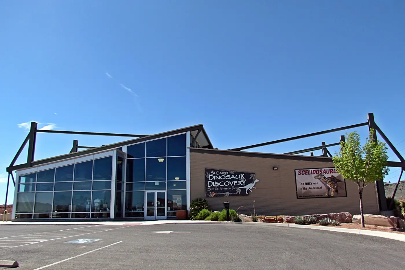 Glass-fronted museum building of the St. George Dinosaur Discovery Site at Johnson Farm under a blue sky