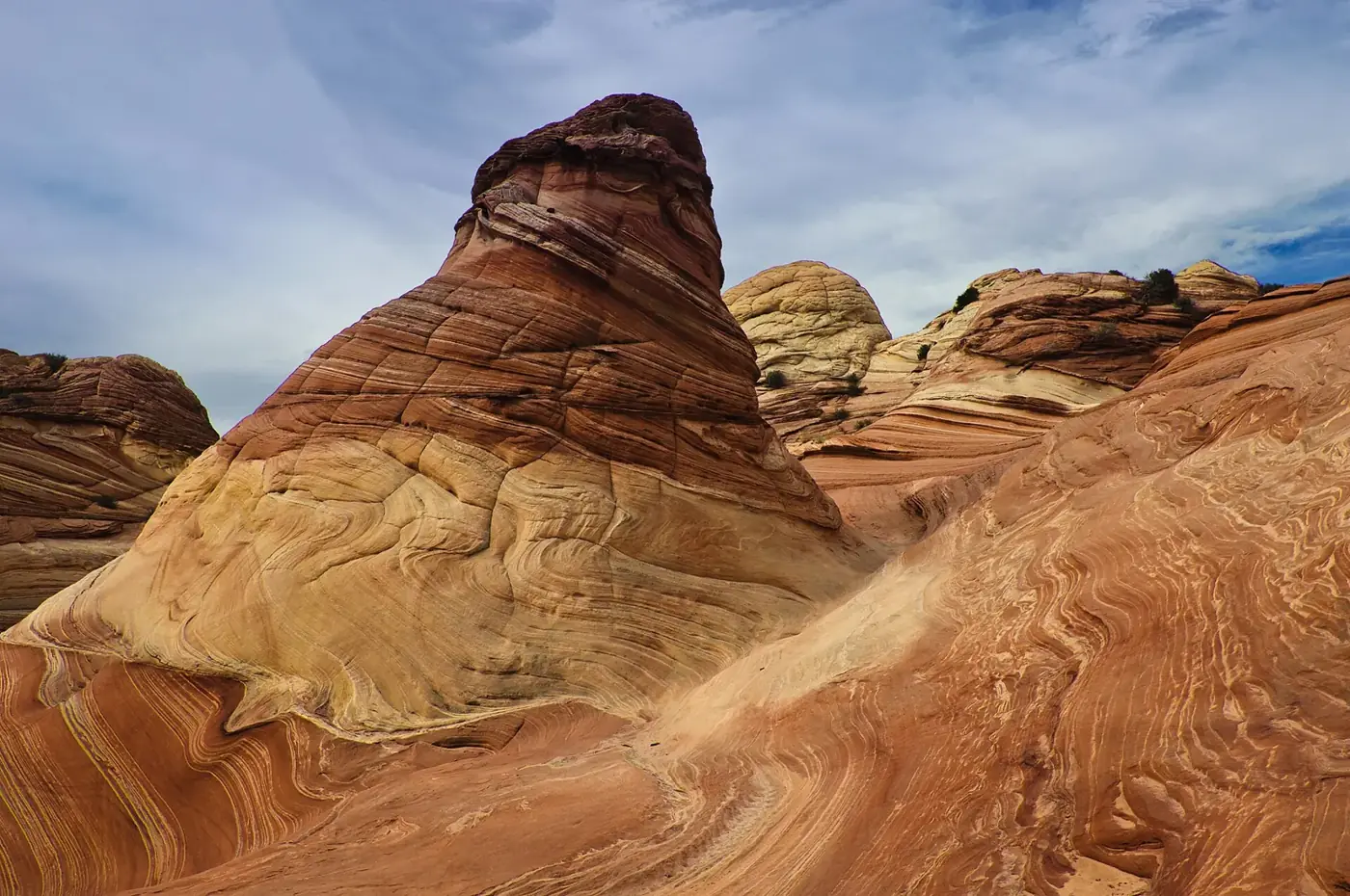 Swirled red and yellow sandstone formations at Coyote Buttes North under a cloudy sky