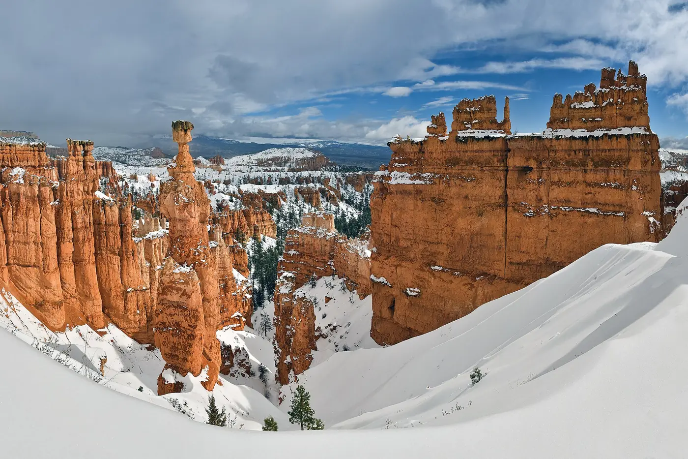 Snow-covered rim beside orange hoodoos including Thor’s Hammer in Bryce Canyon